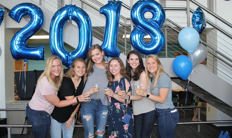 group of graduating women in front of 2018 balloons